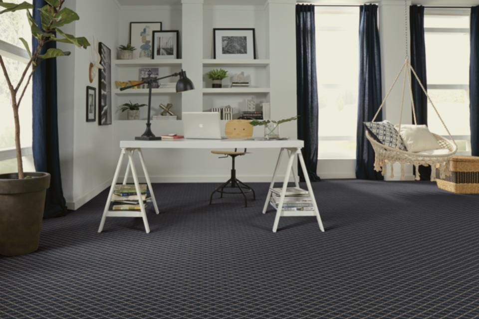 blue patterned carpet in home office with white desk and boho furniture.